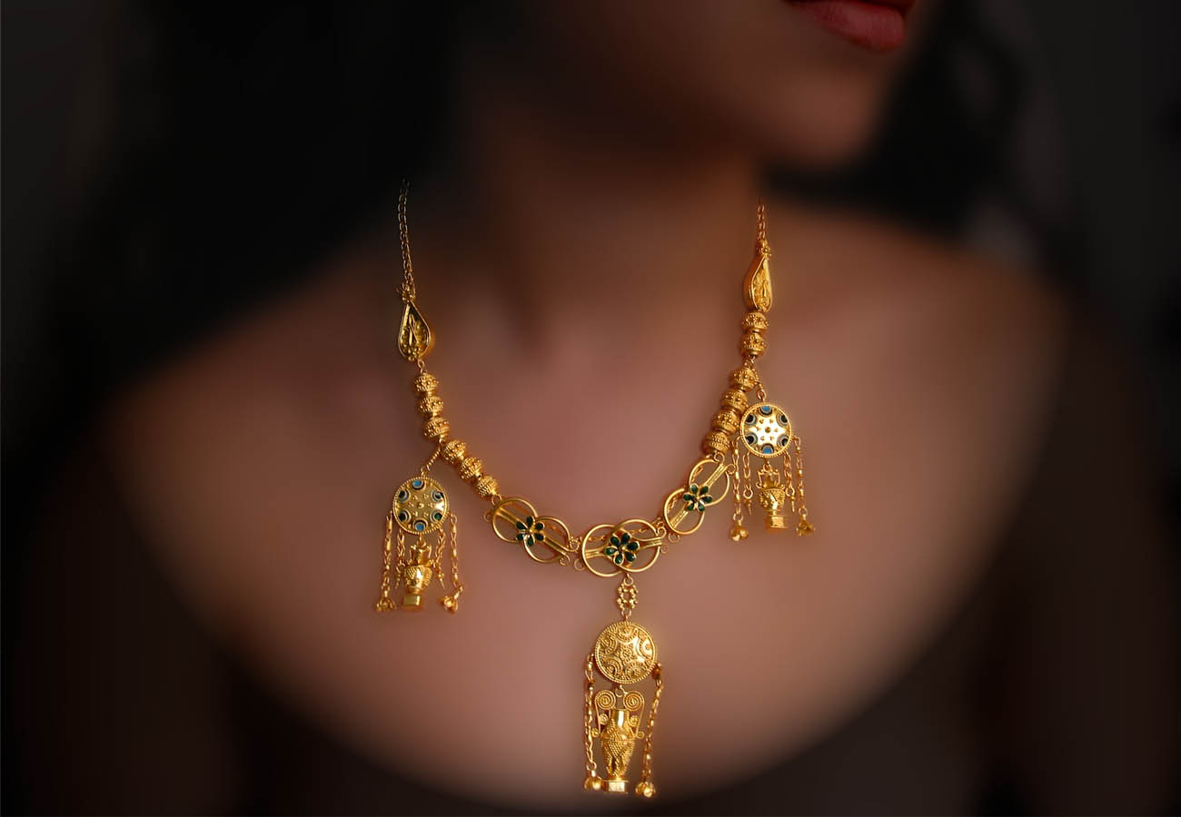 22k gold elements in the shape of vase which are hanging from discs placed in a necklace